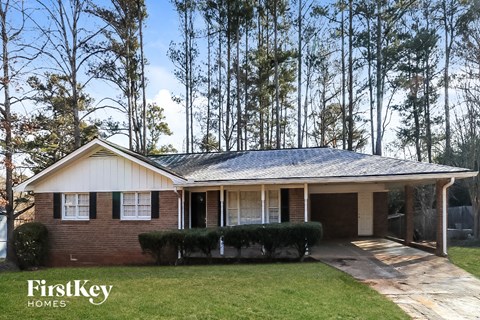 a small brick house with trees in the background