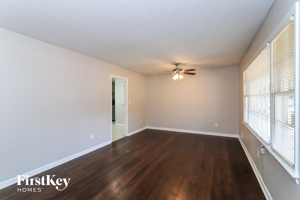 an empty living room with wood floors and a ceiling fan