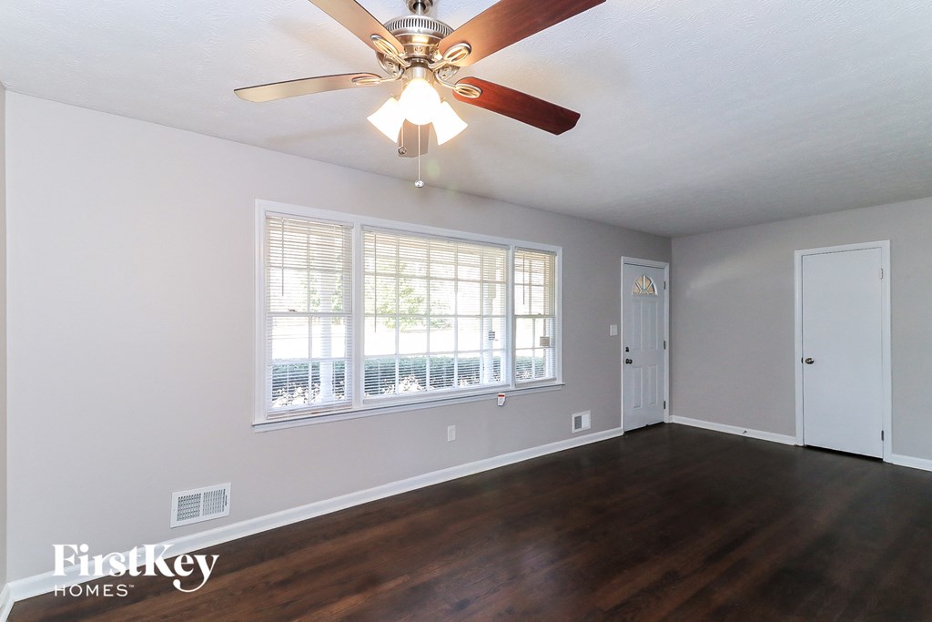 an empty living room with a ceiling fan and a window