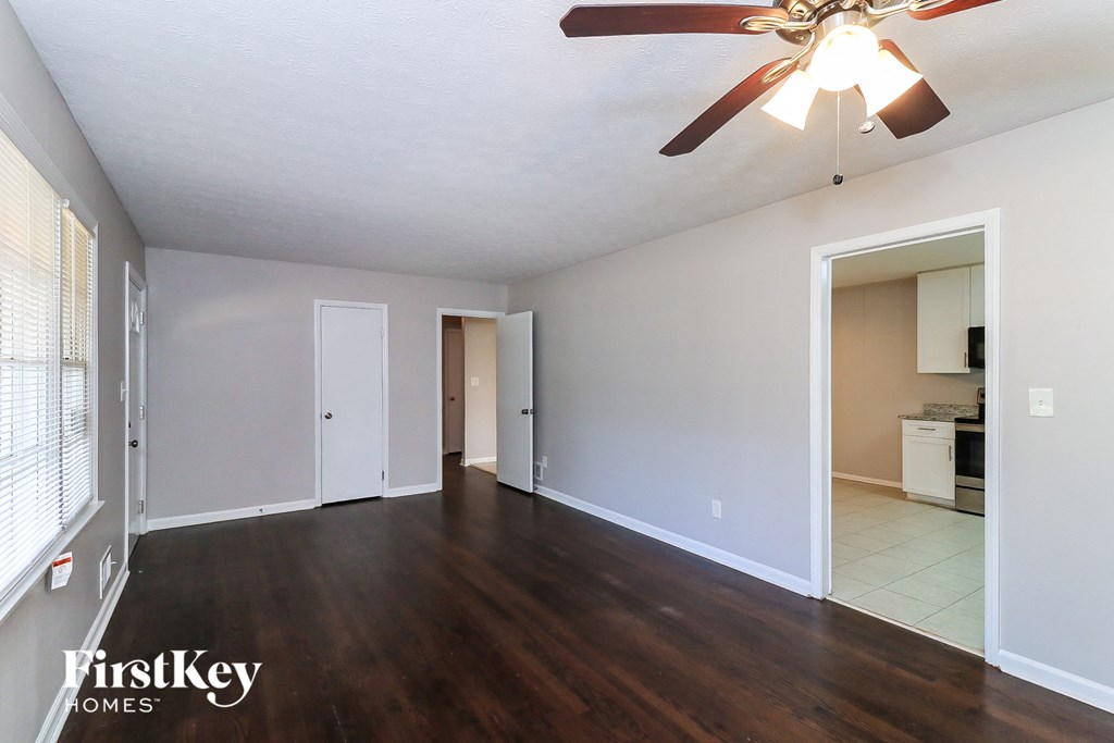 an empty living room with wood flooring and a ceiling fan