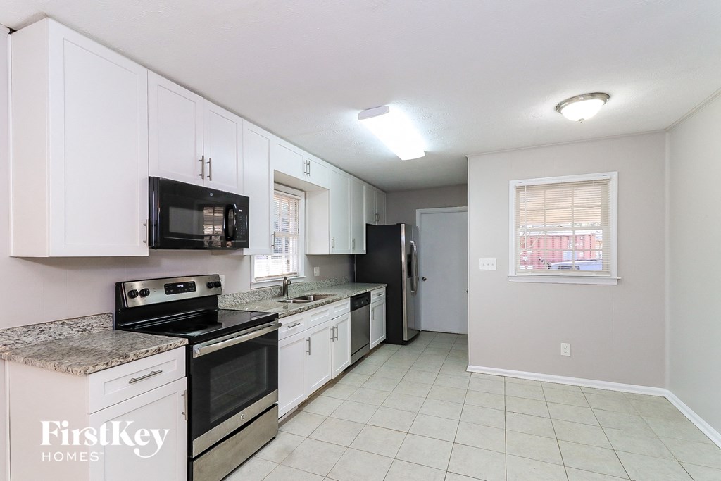 a kitchen with white cabinets and black appliances