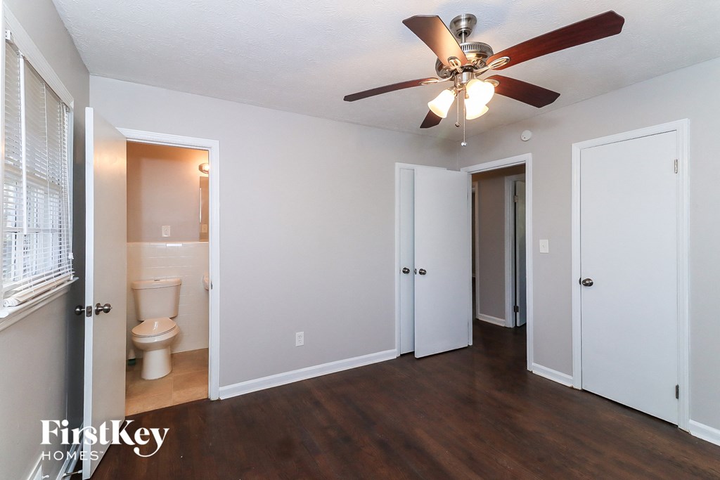 an empty living room with a ceiling fan and a bathroom