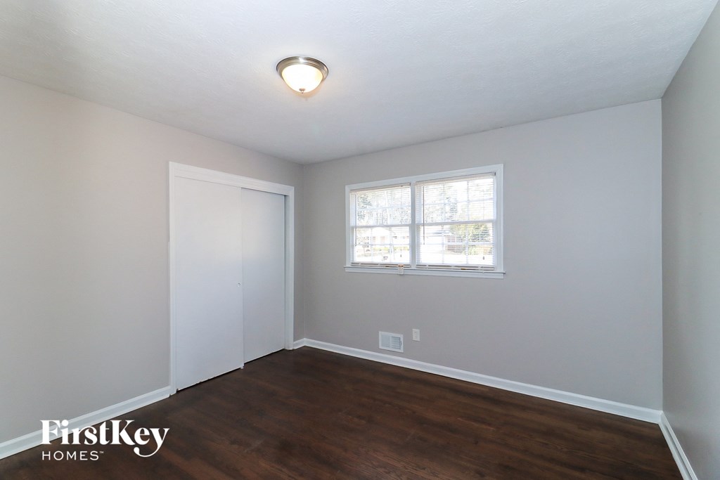 a bedroom with wood flooring and white walls and a window