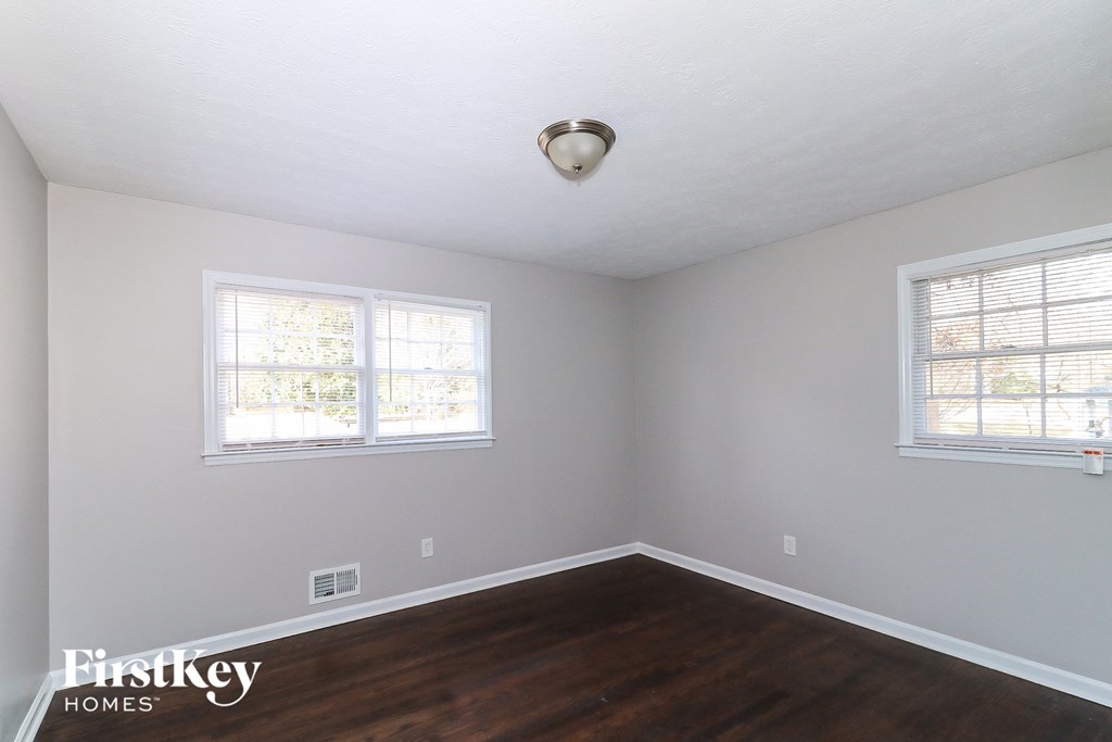 a empty room with wood floors and two windows