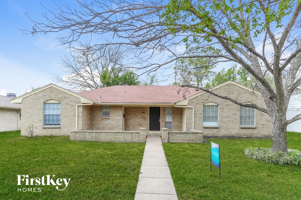 a brick house with a sidewalk and a tree