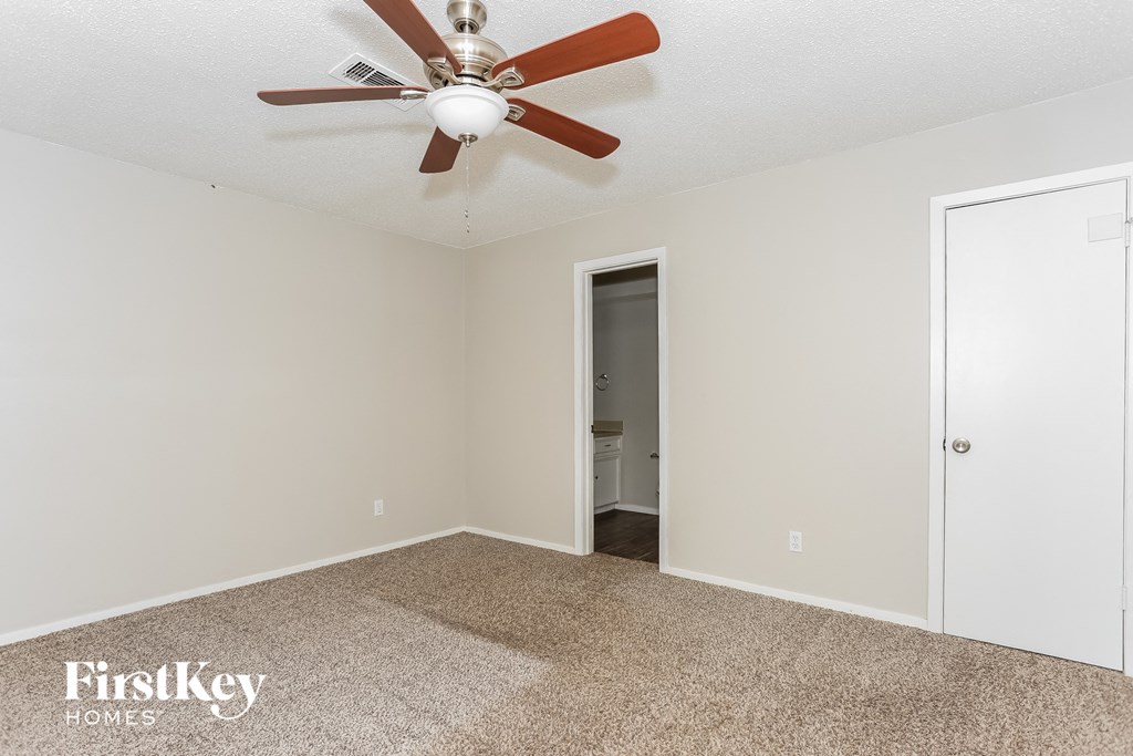 a bedroom with a ceiling fan and a door to a bathroom