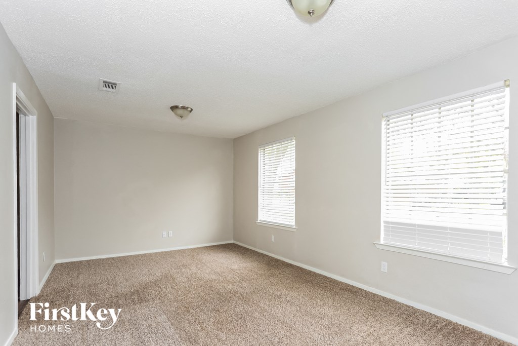 the spacious living room with two windows and beige carpeting