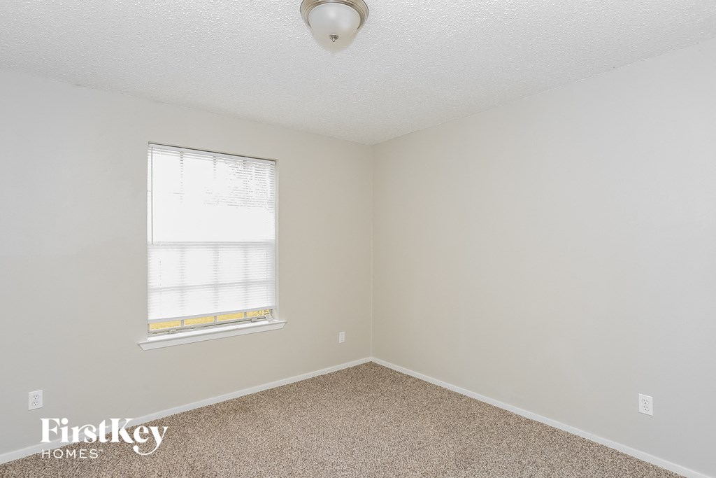 a bedroom with a window and a carpeted floor