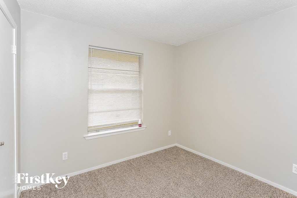 a spacious room with carpet and a window