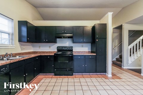 A kitchen with black cabinets and a stove top oven.