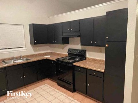 A kitchen with black cabinets and a black stove top oven.