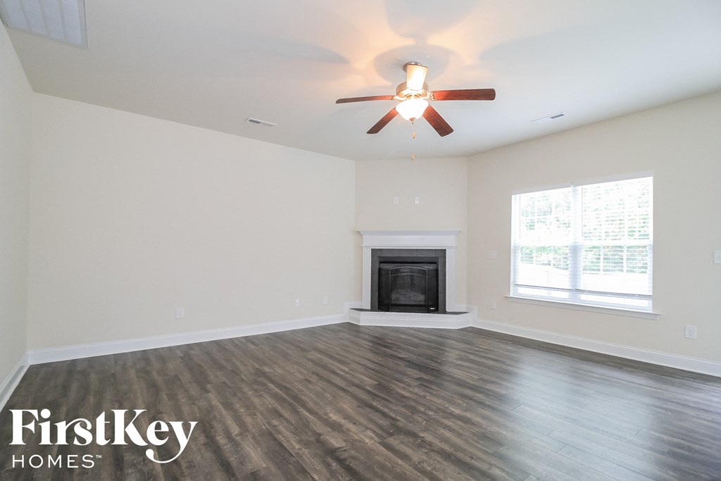 A spacious room with a fireplace and a ceiling fan.