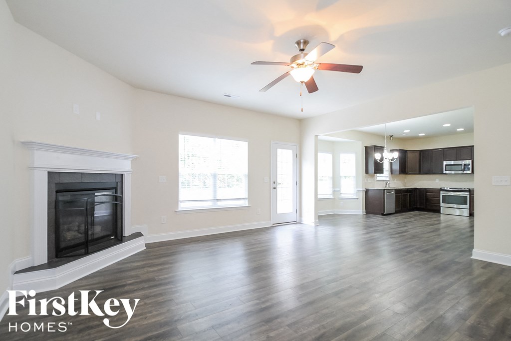 A spacious living room with a fireplace and a ceiling fan.