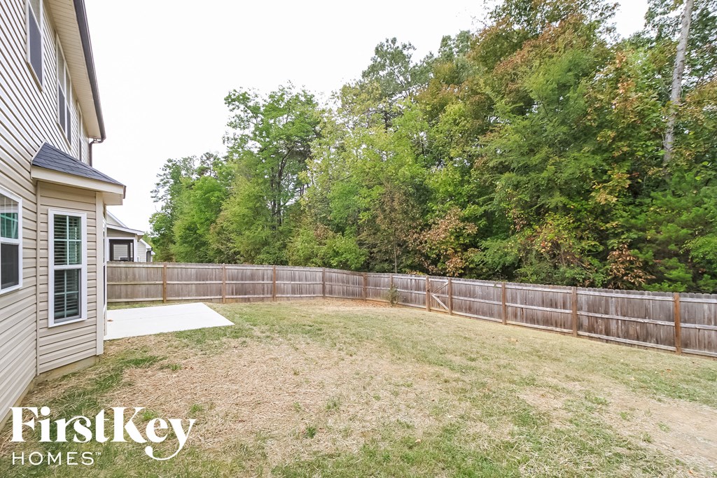 A backyard with a fence and trees in the background.