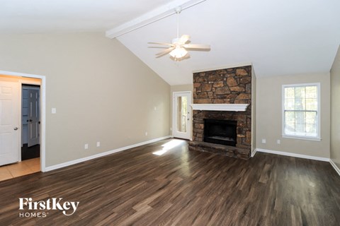 A spacious room with a fireplace and wood flooring.