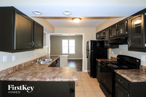 A kitchen with black cabinets and a granite countertop.