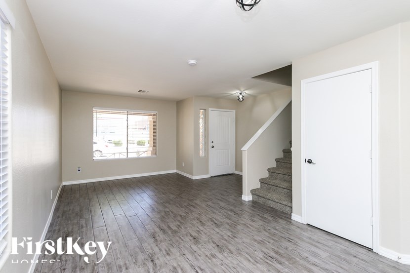 A spacious room with wooden flooring and a staircase leading to another room.