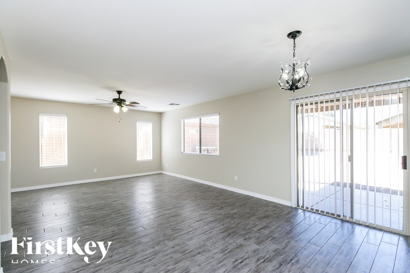 A spacious room with a chandelier, ceiling fan, and sliding glass doors.