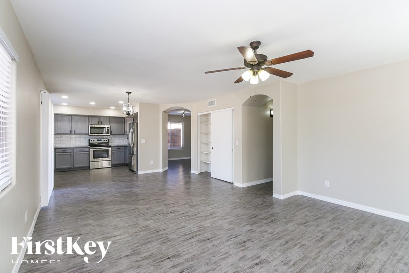 A spacious living room with a ceiling fan and hardwood flooring.
