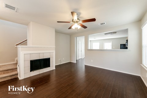 A spacious living room with a fireplace and a ceiling fan.