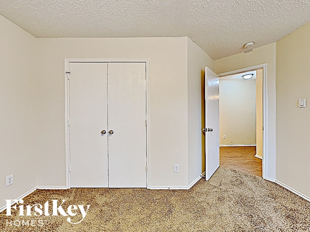 A bedroom with a carpeted floor and a white door.