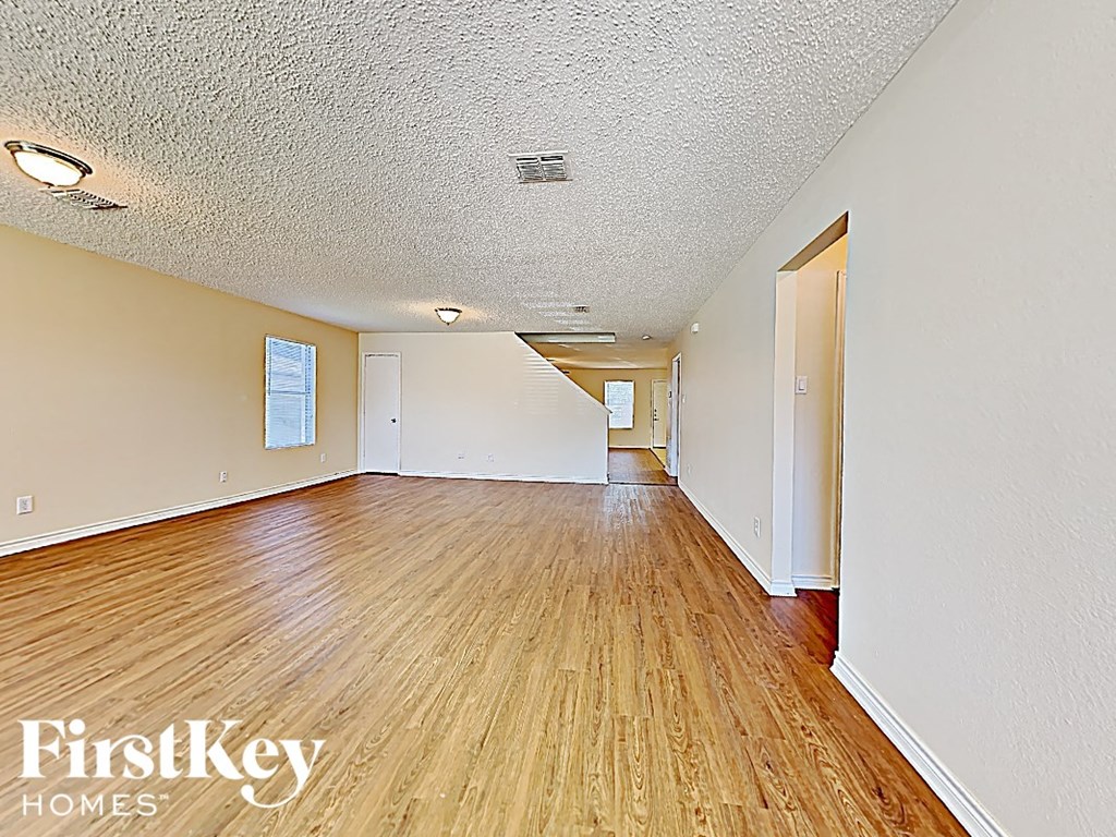 A room with wooden floors and white walls, with a FirstKey Homes logo in the corner.