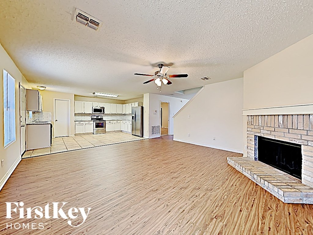 A spacious living room with wood flooring and a fireplace.
