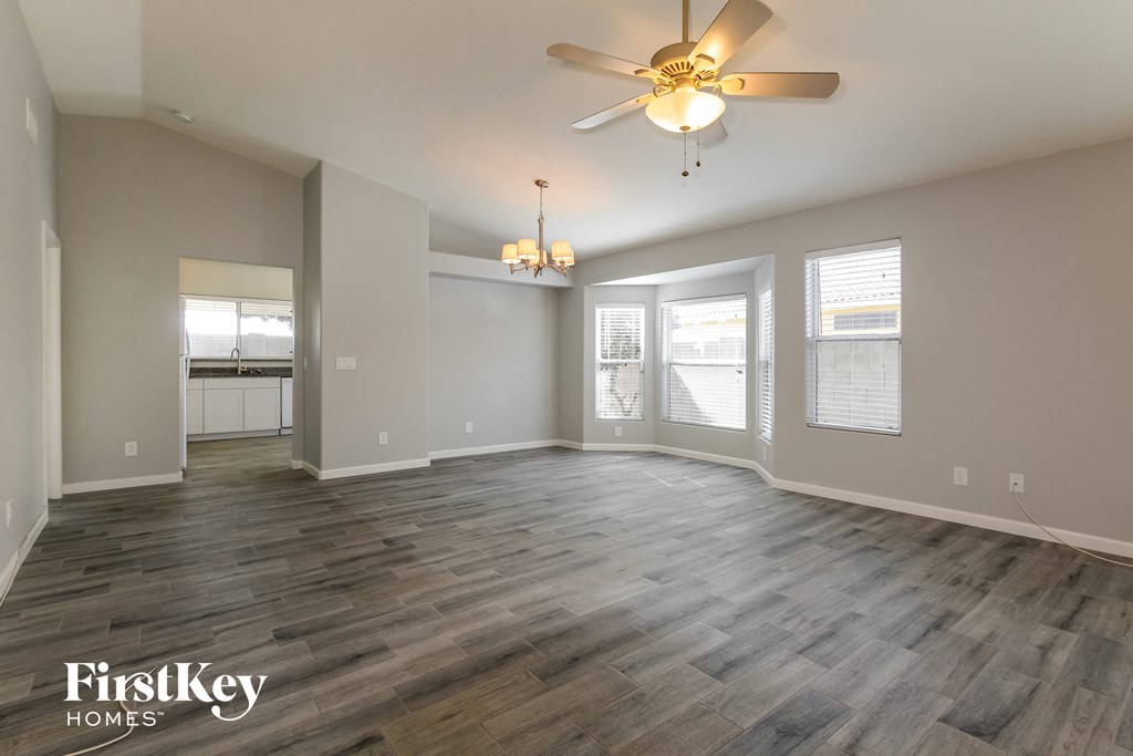 an empty living room with a ceiling fan and windows