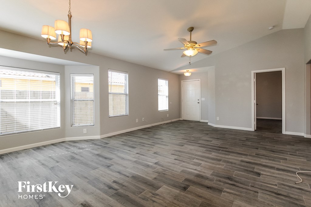 an empty living room with a ceiling fan and windows