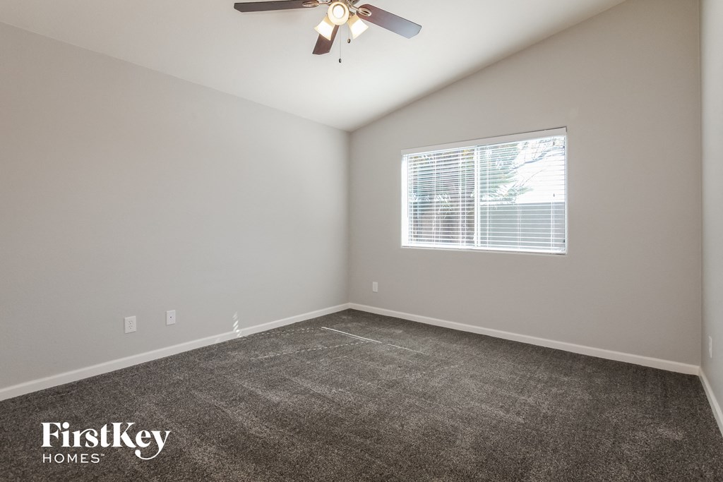 the spacious bedroom with carpeted flooring and a ceiling fan