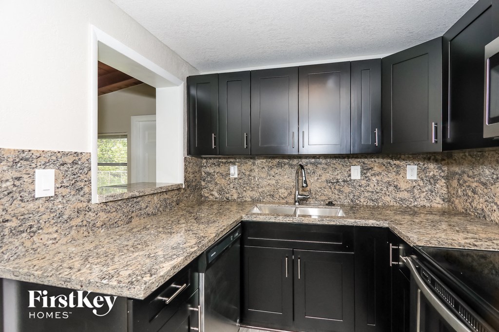 A kitchen with black cabinets and a granite countertop.