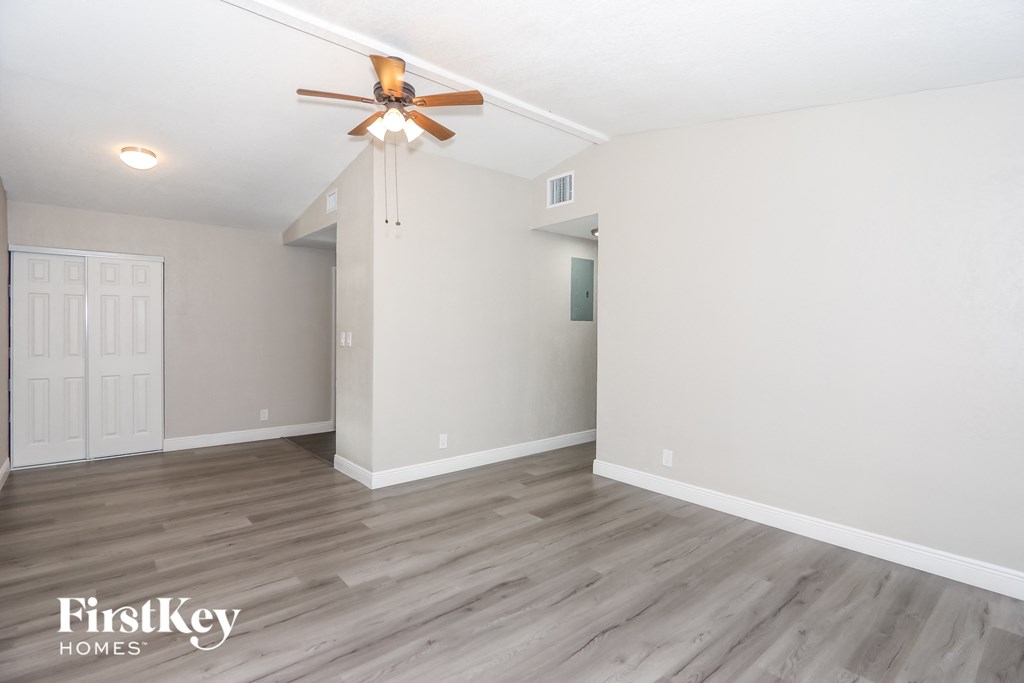 A spacious room with a ceiling fan and lighting fixture.