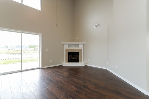 an empty living room with a fireplace and a sliding glass door
