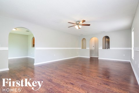 A spacious room with wooden floors and a ceiling fan.