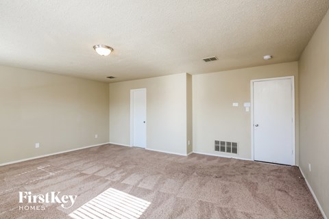a spacious living room with carpet and white walls
