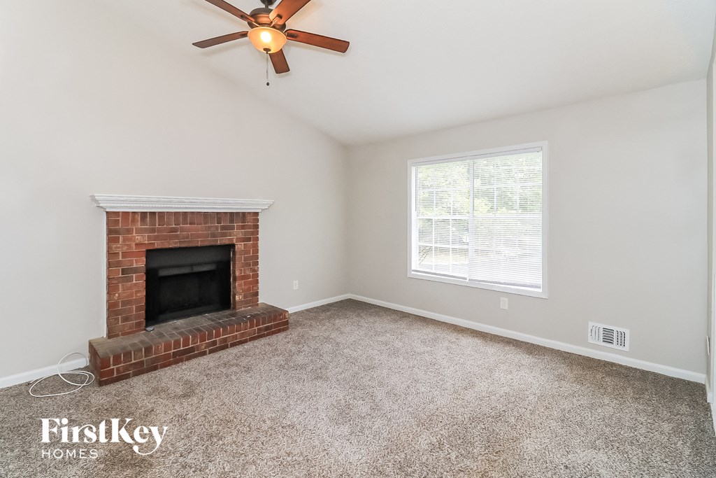 the living room has a brick fireplace and a ceiling fan