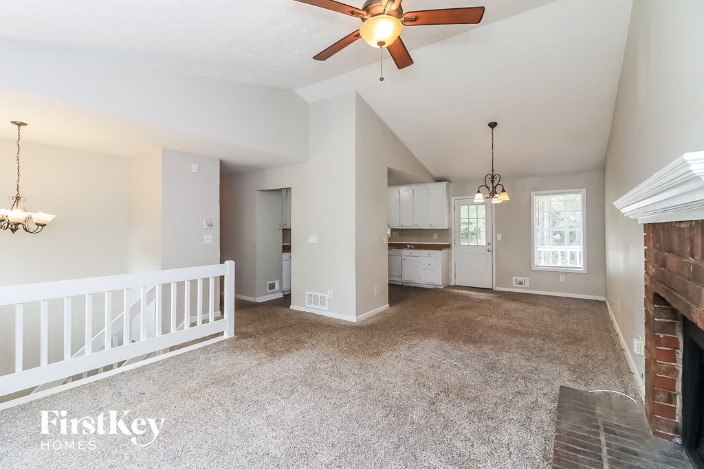 an empty living room with a staircase and a ceiling fan
