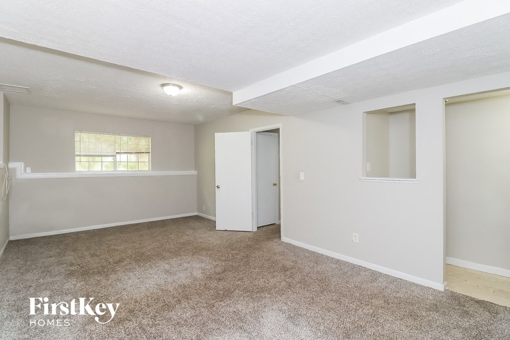 a bedroom with white walls and carpet and a door to a closet