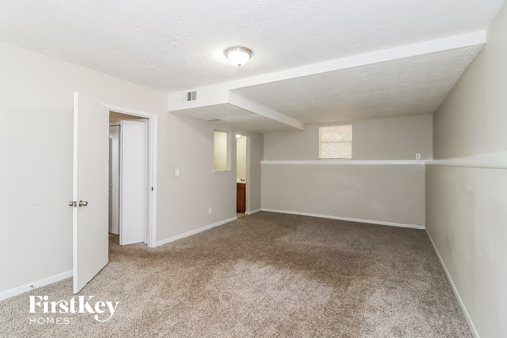 a spacious living room with carpet and white walls