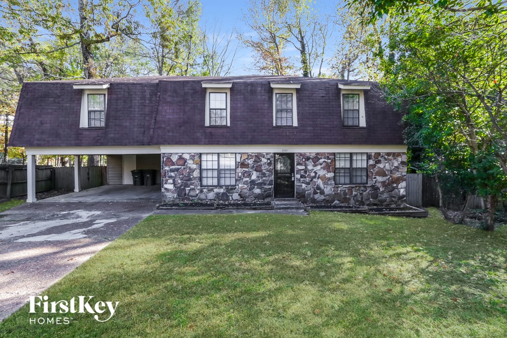 a stone house with a purple roof and a lawn