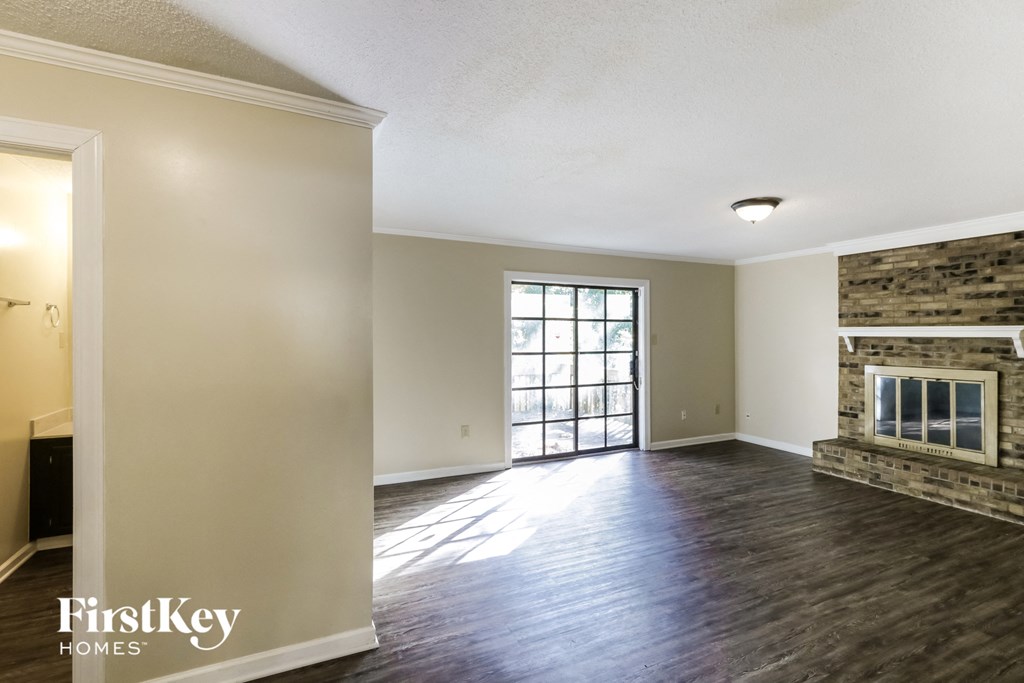 an empty living room with a fireplace and wood flooring