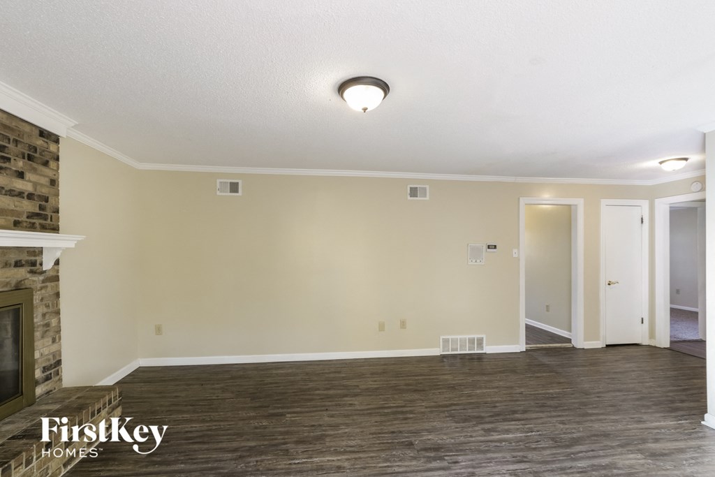 the living room of an empty house with wood flooring and a fireplace