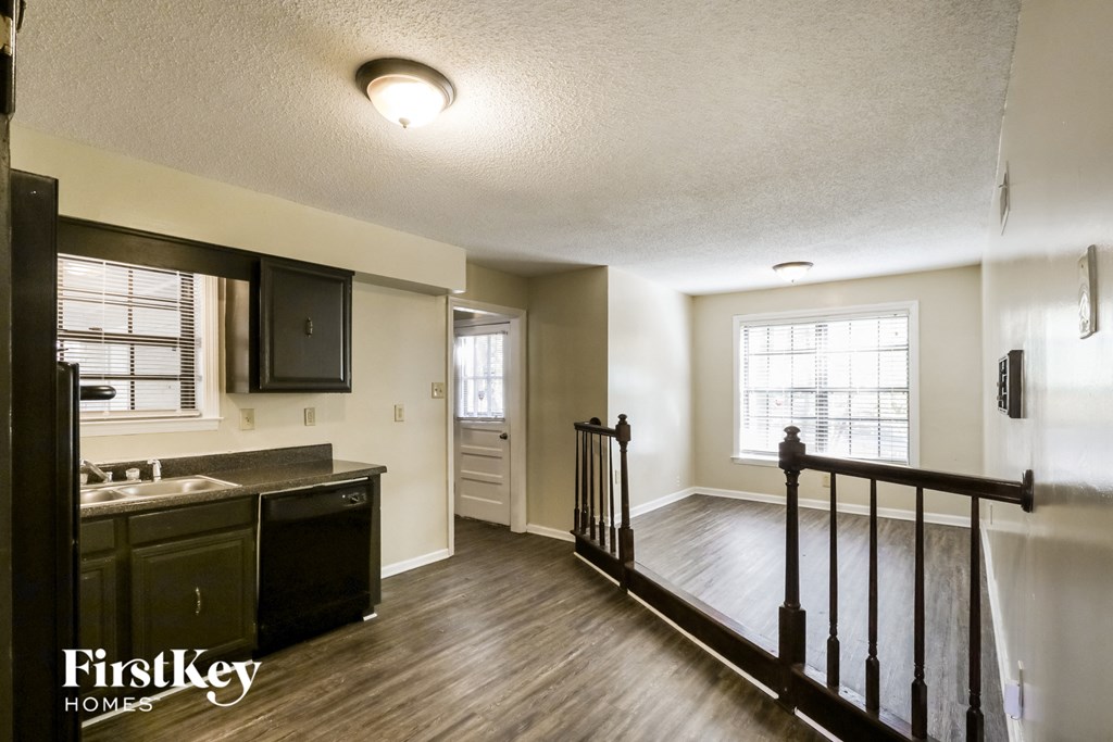 the kitchen and living room of an apartment with a stairway and a kitchen counter