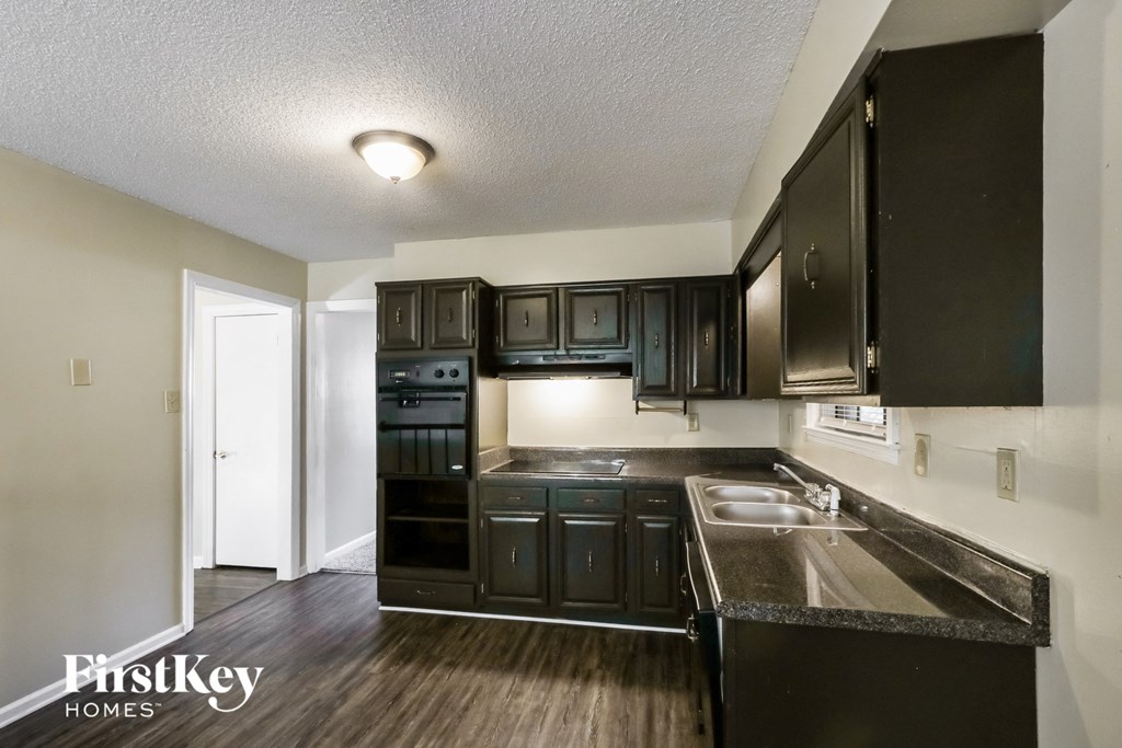an empty kitchen with black cabinets and stainless steel appliances