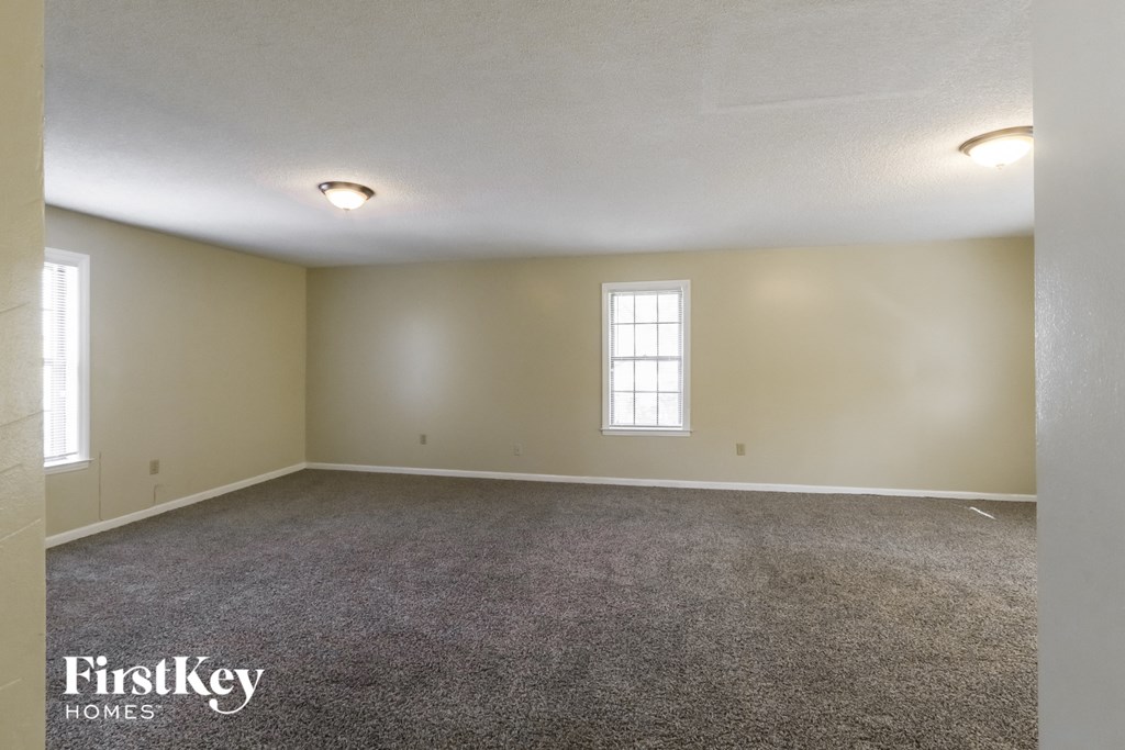 the living room of an empty house with carpet and a window