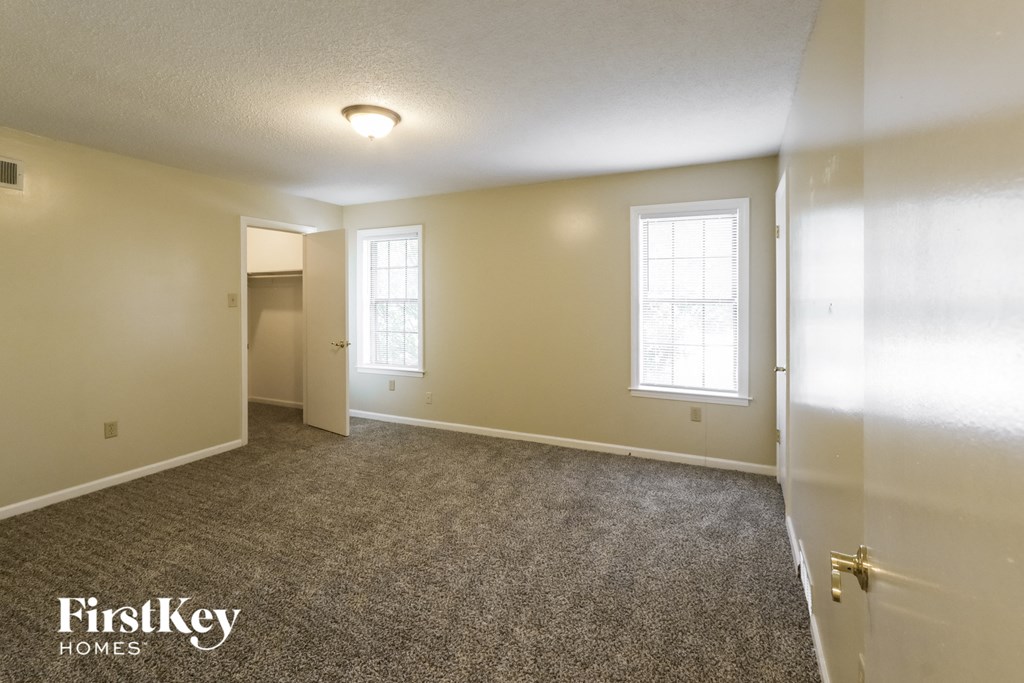 a bedroom with a carpeted floor and a door to a closet