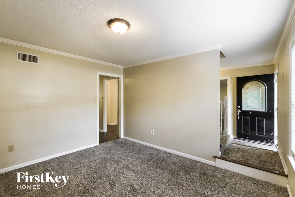 the living room of an empty house with carpet and a black door