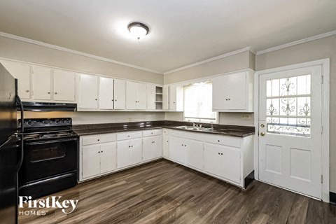 a white kitchen with black appliances and white cabinets