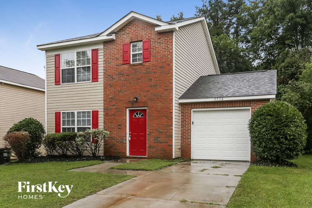 a brick house with a red door and a white garage