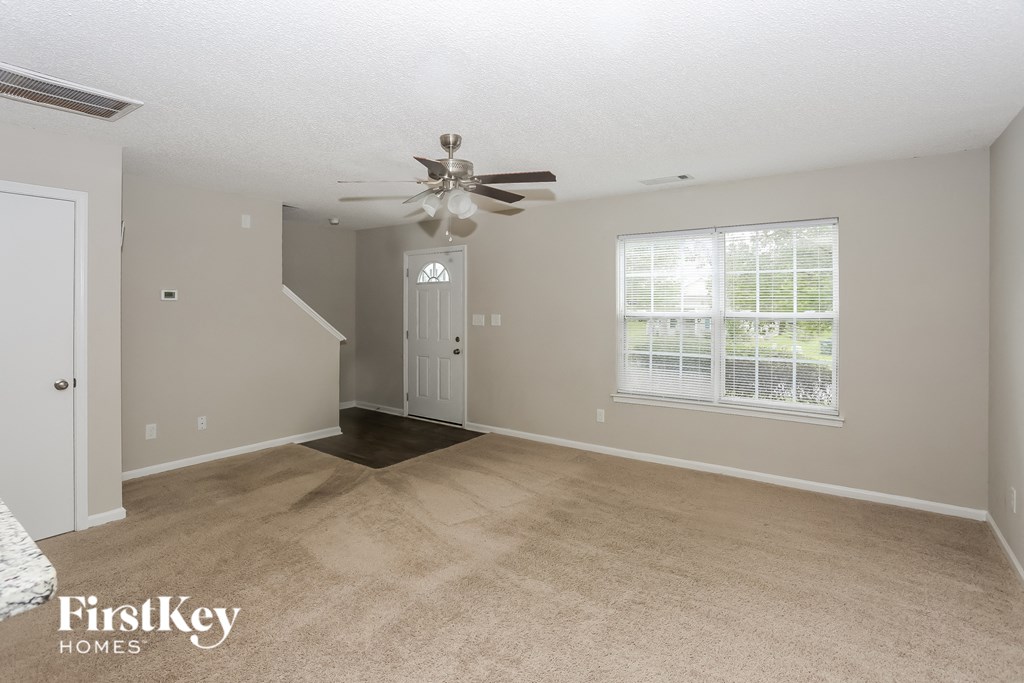 the living room of an empty house with a ceiling fan